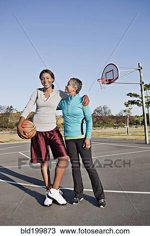 Stock Image - Mother and daughter playing basketball. Fotosearch