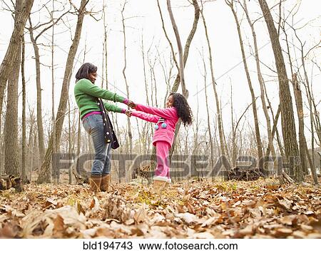 Stock Image - Mother and daughter playing in autumn leaves. Fotosearch