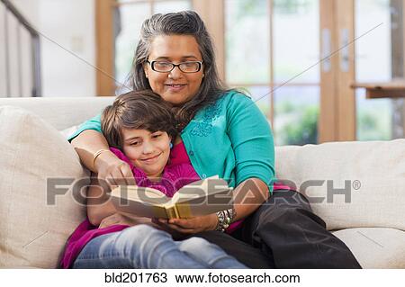 Stock Image - Mother and daughter reading book together. Fotosearch