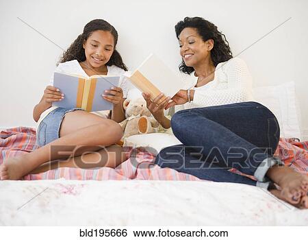 Stock Photograph - Mother and daughter reading in bed. Fotosearch