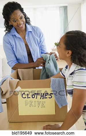 Mother and daughter sorting clothes for clothes drive View Large Photo Image Stock Photo - Mother and daughter sorting clothes for clothes drive. Fotosearch