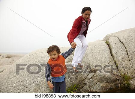 Stock Image - Mother and son climbing on rocks. Fotosearch
