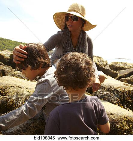 Stock Photography - Mother and sons sitting on rocks. Fotosearch
