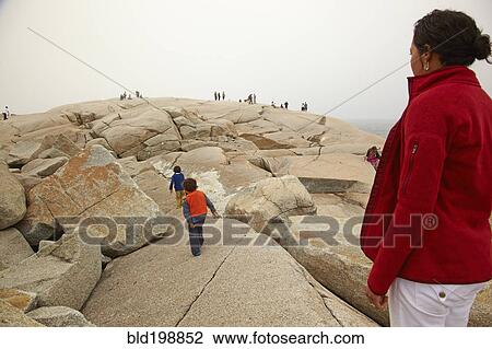 Stock Image - Mother and sons walking on rocks. Fotosearch