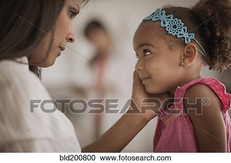 Stock Image - Mother comforting daughter in doctor's office. Fotosearch