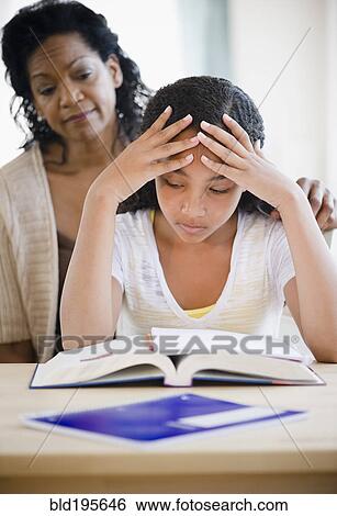 Stock Photograph - Mother comforting frustrated daughter doing homework. Fotosearch