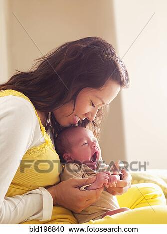 Stock Image - Mother holding newborn baby in her lap. Fotosearch
