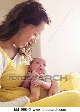 Stock Image - Mother holding newborn baby in her lap. Fotosearch
