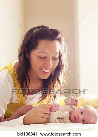 Stock Image - Mother playing with newborn baby. Fotosearch