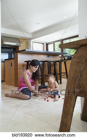 Mother playing with son on floor in kitchen View Large Photo Image Stock Image - Mother playing with son on floor in kitchen. Fotosearch