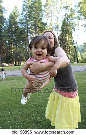 Stock Photograph - Mother swinging daughter outdoors. Fotosearch