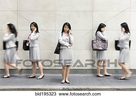 Stock Image - Multiple-exposure of Chinese businesswoman talking on cell phone. Fotosearch