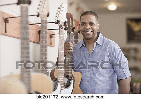 Native American man holding guitar in music store View Large Photo Image Stock Image - Native American man holding guitar in music store. Fotosearch