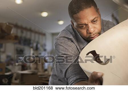 Native American man making guitar in workshop View Large Photo Image Stock Photo - Native American man making guitar in workshop. Fotosearch