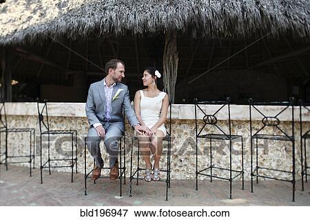 Stock Photo - Newlywed couple sitting on bar stools. Fotosearch
