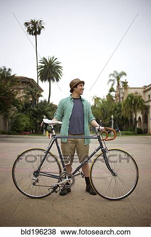 Stock Photo - Pacific Islander man standing with bicycle. Fotosearch