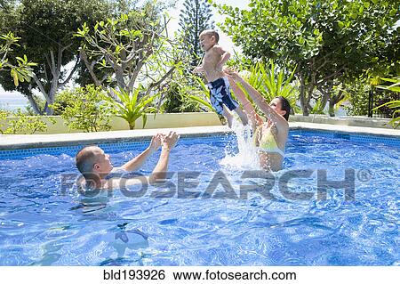 Stock Photograph - Parents throwing son in swimming pool. Fotosearch