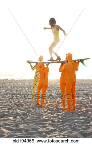 Stock Photograph - People dressed in strange costumes holding surfboard. Fotosearch