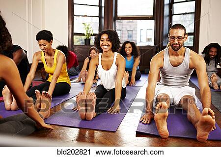 Stock Image - People practicing yoga in class. Fotosearch