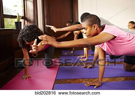 Stock Photograph - People practicing yoga in class. Fotosearch