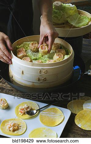 Person putting Asian dumplings in steamer with cabbage View Large Photo Image Stock Photo - Person putting Asian dumplings in steamer with cabbage. Fotosearch