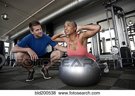 Personal trainer helping woman in health club View Large Photo Image Stock Photo - Personal trainer helping woman in health club. Fotosearch
