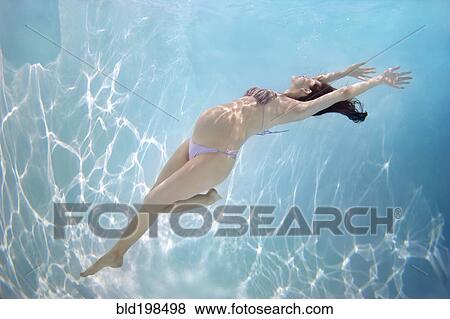 Stock Photo - Pregnant Caucasian woman swimming underwater. Fotosearch