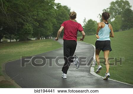 Stock Image - Runners jogging in park. Fotosearch