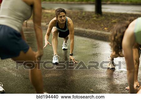 Stock Image - Runners stretching in park. Fotosearch