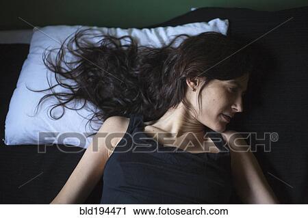Stock Image - Sad mixed race woman laying in bed. Fotosearch