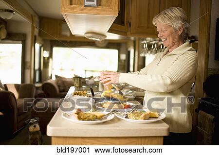 Stock Image - Senior Caucasian woman cooking in motor home. Fotosearch