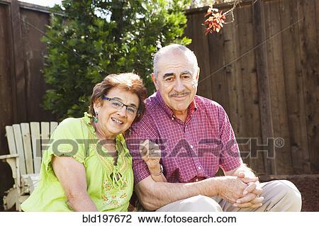 Stock Image - Senior Hispanic couple sitting together outdoors. Fotosearch