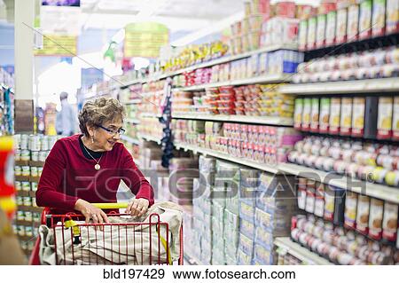 Stock Photo - Senior Hispanic woman shopping in grocery store. Fotosearch