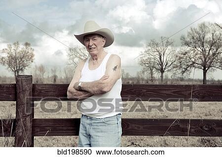 Senior man in cowboy hat standing near wooden fence View Large Photo Image Stock Image - Senior man in cowboy hat standing near wooden fence. Fotosearch