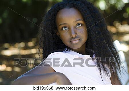 Stock Photo - Serious Black girl sitting in park. Fotosearch