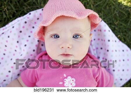 Stock Image - Serious Caucasian baby laying in grass. Fotosearch