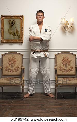 Stock Image - Serious Caucasian man in martial arts uniform standing in elegant room. Fotosearch