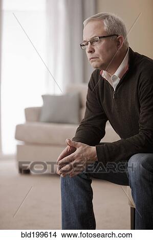 Picture - Serious Caucasian man sitting in living room. Fotosearch