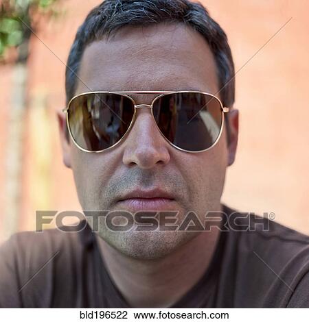 Stock Image - Serious Caucasian man wearing sunglasses. Fotosearch