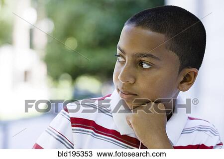 Stock Image - Serious mixed race boy with hand on chin. Fotosearch