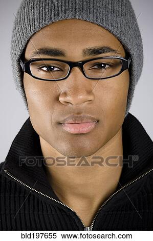 Stock Photography - Serious mixed race man in eyeglasses and cap. Fotosearch