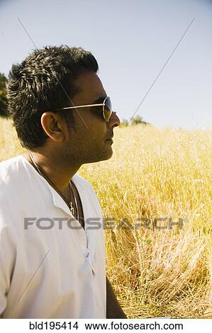 Picture - Serious mixed race man in field. Fotosearch
