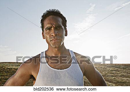 Stock Photograph - Serious Mixed race man standing outdoors. Fotosearch
