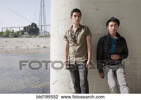 Stock Image - Serious teenage boys leaning against wall. Fotosearch