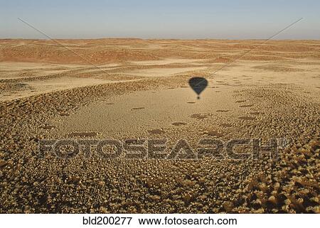 Stock Photo - Shadow of hot air balloon over desert. Fotosearch