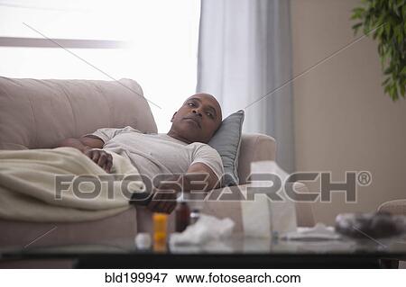 Sick Black man laying on sofa View Large Photo Image Stock Photo - Sick Black man laying on sofa. Fotosearch