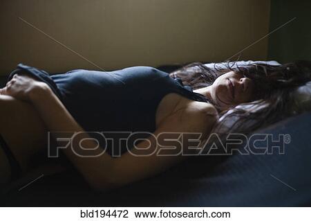 Stock Image - Sleeping mixed race woman laying in bed. Fotosearch