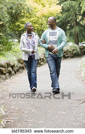 Stock Image - Smiling African American couple walking in park. Fotosearch