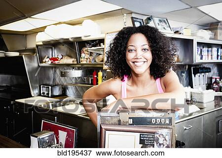 Smiling African American woman leaning on cash register in diner View Large Photo Image Stock Photo - Smiling African American woman leaning on cash register in diner. Fotosearch