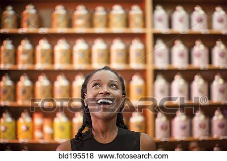 Smiling Black woman looking up in shop View Large Photo Image Stock Photo - Smiling Black woman looking up in shop. Fotosearch